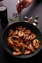 жареные креветки в сковороде на черном фоне