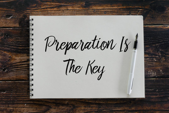 Top view of pen and notebook written with Preparation Is The Key.
