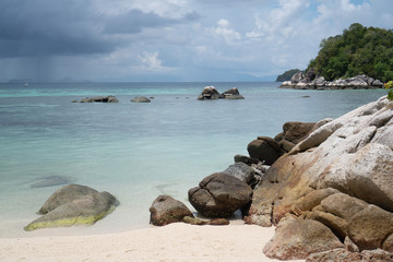 Fototapeta na wymiar Sandy beach with rocks over sea and cloudy sky. Koh Lipe island in Thailand