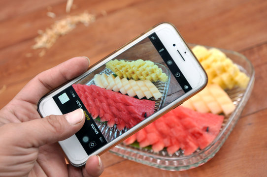 close up mobile fruit photography take a picture of watermelon pineapple cantaloupe wood table hand iphone 