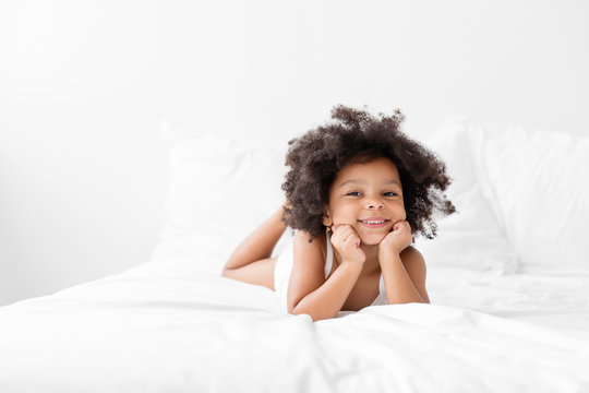 Cute African American girl with Afro lying on bed