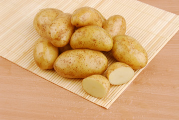 Lots of raw potatoes on bamboo stand on gray isolated background