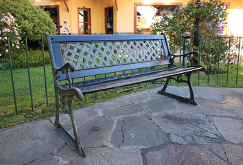 Empty Dark Colored Wood and Wrought Iron Bench in the Garden