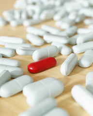 Rote Pille zwischen vielen weißen Tabletten