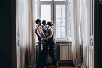 family of three staying near the window and huging each other
