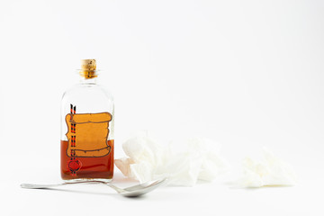 Arrangement of a spoon, handkerchiefs and a vintage medicine bottle with cork filled with orange...