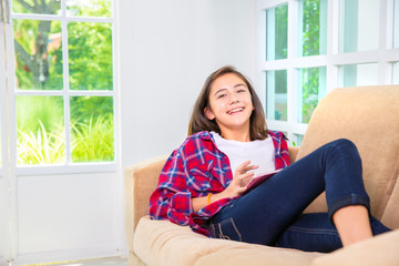Caucasian teenage girl playing smartphone or tablet pc on sofa at home
