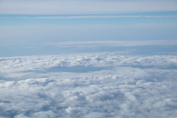 Aerial view from plane window with blue sky and white clouds