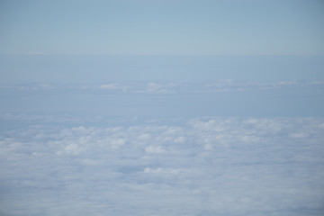 Aerial view from plane window with blue sky and white clouds