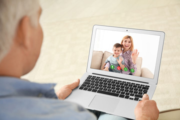 Closeup view of senior man talking with family members via video chat at home