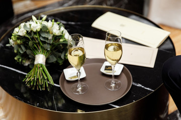 Two glasses of champagne next to a bouquet of flowers