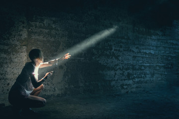 Fototapeta na wymiar A woman in a dark cave illuminated by a ray of light.