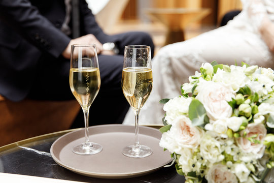 Two glasses of champagne next to a bouquet of flowers