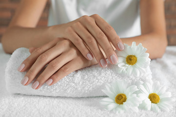 Obraz na płótnie Canvas Woman with smooth hands and flowers on towel, closeup. Spa treatment