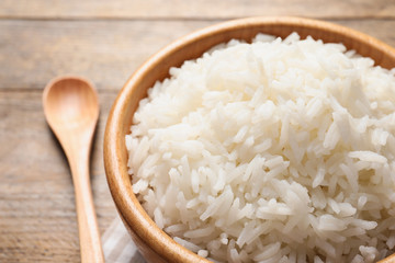 Bowl of delicious rice on wooden table, closeup