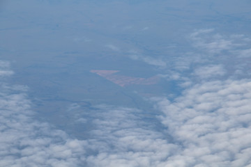 Aerial view from plane window with blue sky and white clouds
