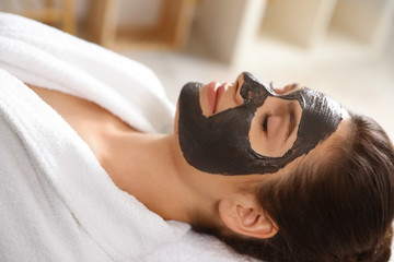 Obraz na płótnie Canvas Beautiful woman with black mask on face relaxing in spa salon