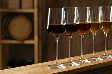 Glasses of different wines in cellar, space for text. Expensive collection