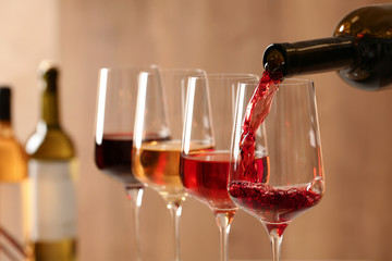 Pouring wine from bottle into glass on blurred background, closeup - obrazy, fototapety, plakaty