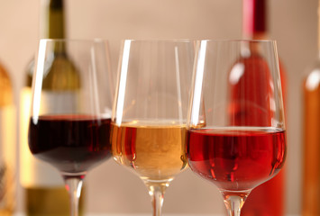 Glasses of different wines against blurred background, closeup