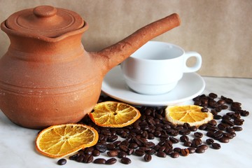 brown clay dishes, white clean Cup and saucer, roasted coffee beans and dried orange, selective focus