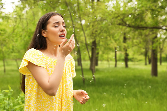 Young woman suffering from seasonal allergy outdoors, space for text