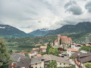 Fototapeta na wymiar general view of an alpine valley with old town and church surrounded by mountains