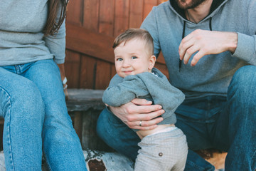 The cute baby boy with family on wooden house background outdoors, country life nature concept