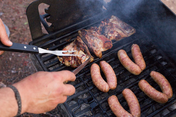 Summer barbecue, grilling sausages and chicken