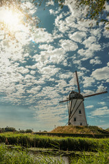 Old windmill next to canal and sunlight at Damme