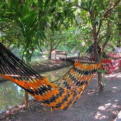 Hand-crafted hammocks hanging in the garden with a canal to relax