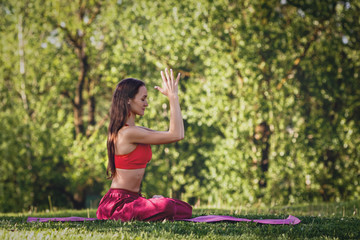 Naklejka na ściany i meble Young woman practicing yoga outdoors. Female meditate outdoor in the summer city park.