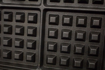 A closeup shot of a waffle iron and the common waffle pattern