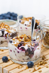 glasses with healthy dessert with blueberries, yogurt and granola, vertical closeup