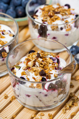 glasses with healthy dessert with blueberries, yogurt and muesli, vertical top view