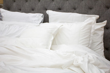 A bed setting featuring white pillows, sheets and blanket