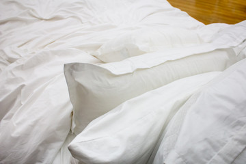 A bed setting featuring white pillows, sheets and blanket