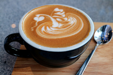 Closeup a Cup of Hot Cappuccino Coffee with Tea Spoon Served on Wooden Tray