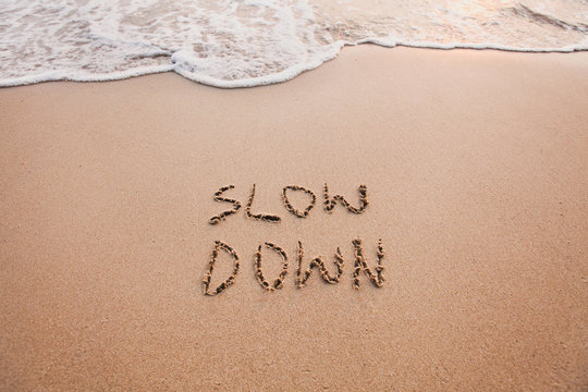 slow down, mindfulness concept written on sand