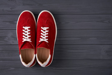 Top view of casual red suede trainers on grey wooden planks