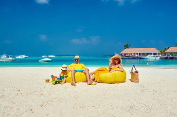 Fototapeta na wymiar Family on beach, young couple in yellow with three year old boy. Summer vacation at Maldives.