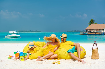 Fototapeta na wymiar Family on beach, young couple in yellow with three year old boy. Summer vacation at Maldives.