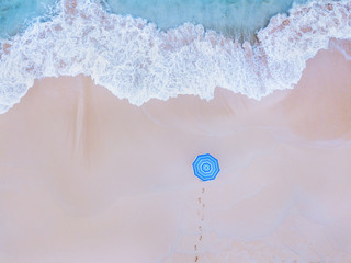 Travel to beautiful beach, holidays, vacation getaway on paradise island, aerial top down view of ocean wave and person with blue umbrella.
