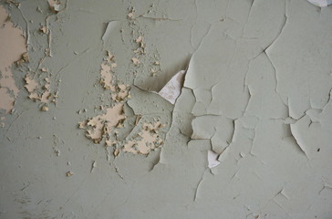 Old wall: chipped, partially peeled-off white, beige and green paint. 