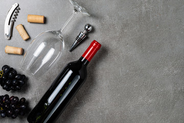 Wine bottle, glass, opener and grapes on concrete background. Copy Space.