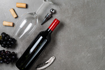 Wine bottle, glass, opener and grapes on concrete background. Copy Space.