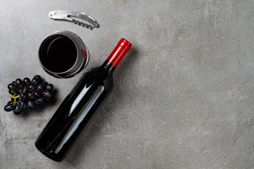 Wine bottle, glass, opener and grapes on concrete background. Copy Space.
