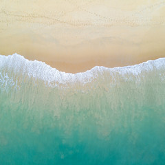Aerial view of turquoise ocean wave reaching the coastline. Beautiful tropical beach from top view....