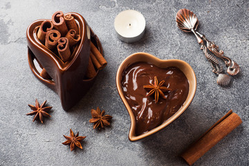 Chocolate paste with cinnamon and anise. Fondue with chocolate on a dark concrete table.