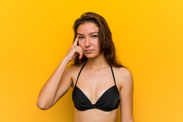 Young european woman wearing bikini showing a disappointment gesture with forefinger.